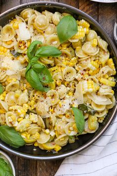 a pan filled with pasta and vegetables on top of a wooden table