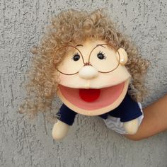 a person holding a stuffed animal with curly hair and glasses on it's face