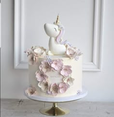 a white cake with pink flowers and a unicorn figurine sitting on top of it