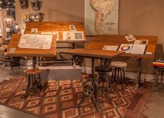 a room filled with lots of wooden tables and stools next to a map on the wall