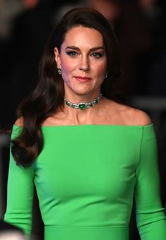 a woman in a green dress is looking off to the side with her hand on her hip