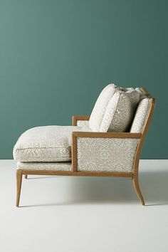 a chaise lounge chair in front of a wall with a green painted background and white flooring