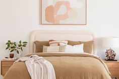 a bedroom with a bed, nightstands and painting on the wall above it's headboard