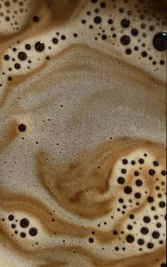 a close up view of some liquid in a bowl with brown and white designs on it