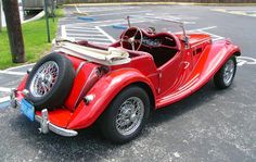 an old red car parked in a parking lot