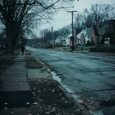 a person walking down the street in front of houses on a gloomy day with no cars