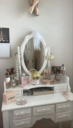 a white dresser topped with a mirror and lots of clutter