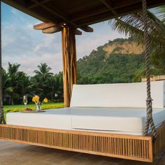 a white bed sitting on top of a wooden porch next to a lush green field