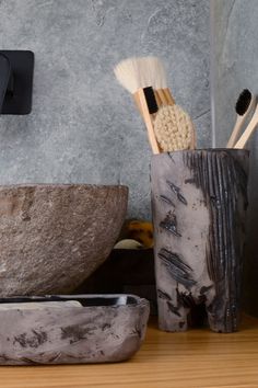 two toothbrushes are in a vase next to a stone bowl