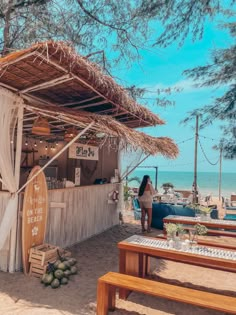 a woman standing in front of a food stand on the beach