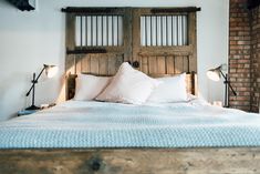 a bed with white pillows and wooden headboard next to two lamps on either side