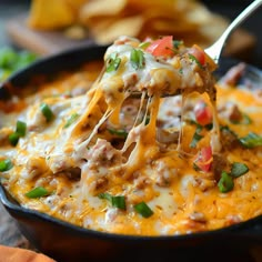 a spoon full of cheesy ground beef casserole with cheese and green onions