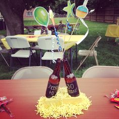 two beer bottles sitting on top of a table next to some balloons and streamers