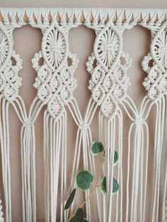 a white macrame wall hanging with green plants