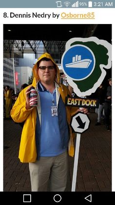 a man standing next to a sign with a drink in his hand and wearing a yellow jacket