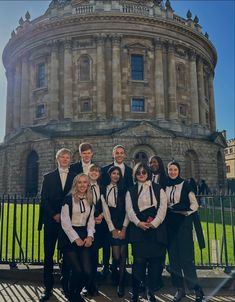 a group of young people standing next to each other in front of a large building