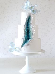 a three tiered white cake with blue flowers on top