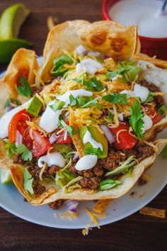 three tacos on a plate with salsa and tortilla chips next to it