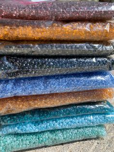 there are many different colors of beads in the plastic bag on the ground and one is blue, yellow, green, orange