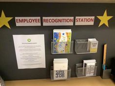 an employee recognition station is displayed on the wall in front of a desk with various items