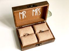 an open wooden box with four rings in it that say mr and mrs on the inside