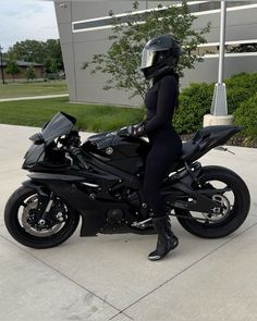 a woman sitting on top of a motorcycle in front of a building with a helmet