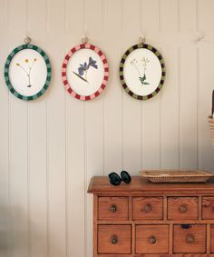 three plates are hanging on the wall above a dresser