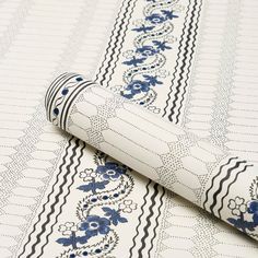 a close up of a wallpaper with blue flowers and stripes on white paper that is laying on the ground