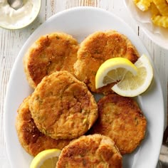 fried crab cakes on a plate with lemon wedges next to the rest of the meal