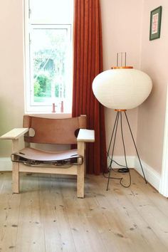 a living room with a chair, lamp and large window in it's corner