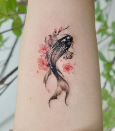 a woman's arm with a fish and flowers tattoo on the left side of her body