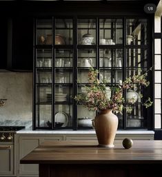 a vase filled with flowers sitting on top of a wooden table next to a window