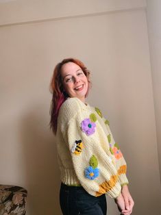 a woman with red hair is smiling and wearing a sweater that has flowers on it