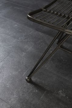 a metal chair sitting on top of a gray floor next to a black tile floor