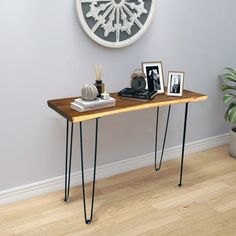 a wooden table with hairpin legs in front of a white clock on the wall