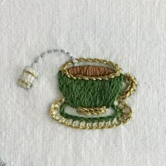 a piece of fabric with some gold chains around it and a green cup in the middle