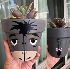 two potted plants with faces painted on them are being held in front of a window