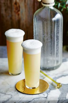 two drinks sitting on top of a table next to a vase with flowers in it