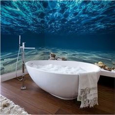 a bath tub sitting in the middle of a bathroom next to a wall with an underwater scene on it