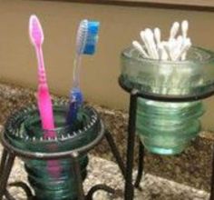 two toothbrushes are sitting in glass containers on a counter top next to each other