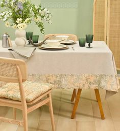 the table is set for two with plates and cups on it, along with vases filled with flowers