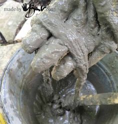 a bucket full of mud with a hand holding it up to the top of it