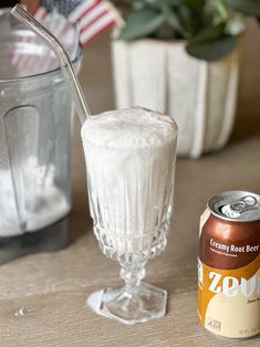 a can of soda next to a glass with ice cream in it and an american flag on the table