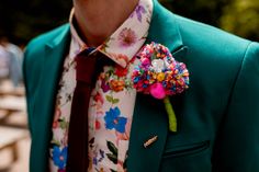 a man wearing a green jacket and colorful flower boutonniere on his lapel