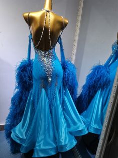 a blue dress with feathers and beads on it is displayed in front of a mirror