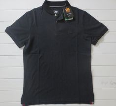 a black polo shirt hanging on a white wall with a tag attached to the collar