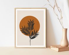 an orange and black art print on a shelf next to a vase with dried plants