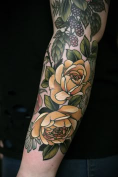 an arm with yellow roses and leaves on it