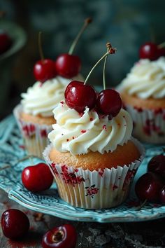 cupcakes with white frosting and cherries on a plate