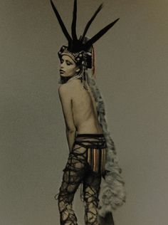 a woman with an elaborate headdress and feathers on her head